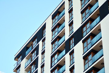 Fragment of a facade of a building with windows and balconies. Modern home with many flats.