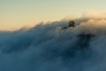 Buddhist temple showing through fog and clouds on mountain top, Emei Mountain, China