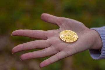 Female open hand holding a bitcoin or cryptocurrency in the center with green background
