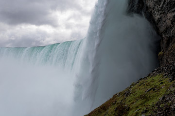 Green grass on rocky edge in front of epic waterfall
