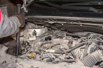 A hand technician checking or fixing the engine of a modern car.