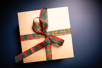 Carton box on blue background decorated with ribbon. Christmas theme.