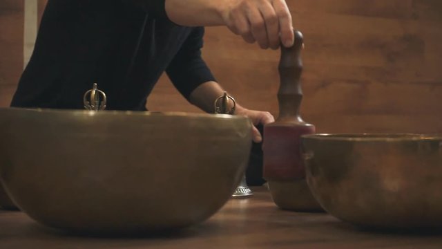 A man's hand strikes the Tibetan singing bowl closeup