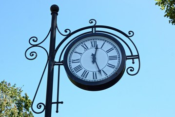 Fototapeta na wymiar big round clock on a black pillar against a blue sky