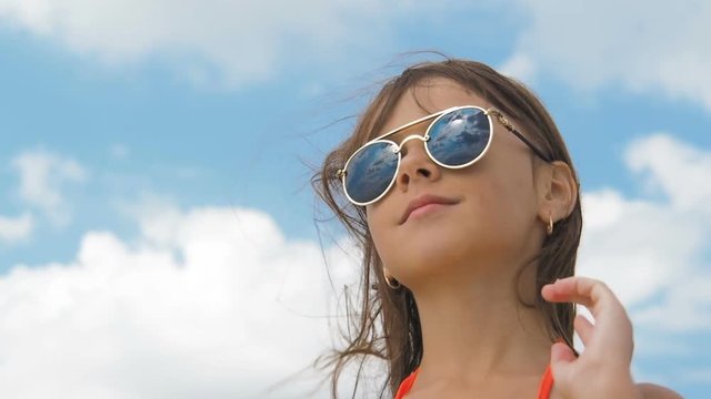 Child in sunglasses. Portrait of a little girl in sunglasses against the background of the sky.