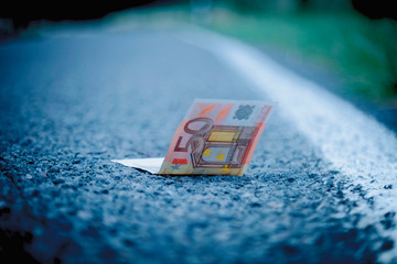 Good luck to find money as a symbol of profit. Euro banknotes on the road.