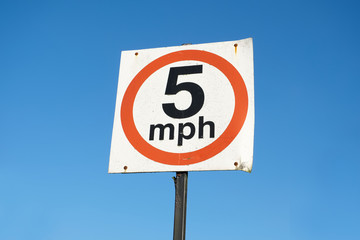 5 mph speed limit sign against blank empty blue sky