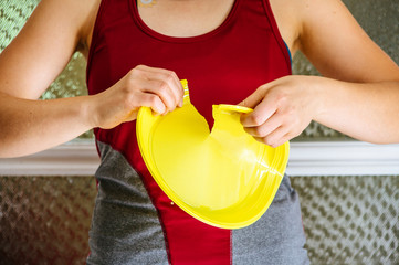 Europe ban on plastic dishes concept. Woman destroys yellow plastic plate.