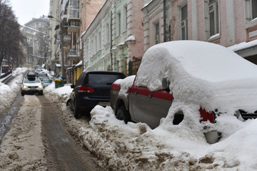 cars covered snow on winter street after blizzard