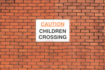 Fototapeta na wymiar Caution children crossing road safety sign on school wall