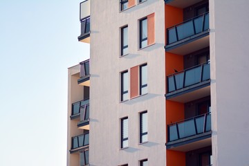  Fragment of a facade of a building with windows and balconies. Modern home with many flats.