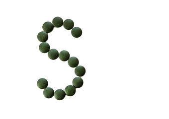 Letter S made out of spirulina food supplement tablets.