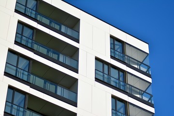 Fragment of a facade of a building with windows and balconies. Modern home with many flats.