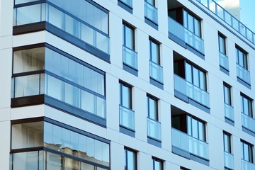 Fragment of a facade of a building with windows and balconies. Modern home with many flats.