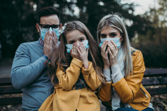 Young family in protective mask outdoors in park. Air pollution concept.