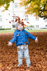 Kleiner Junge wirft Herbstflätter hoch