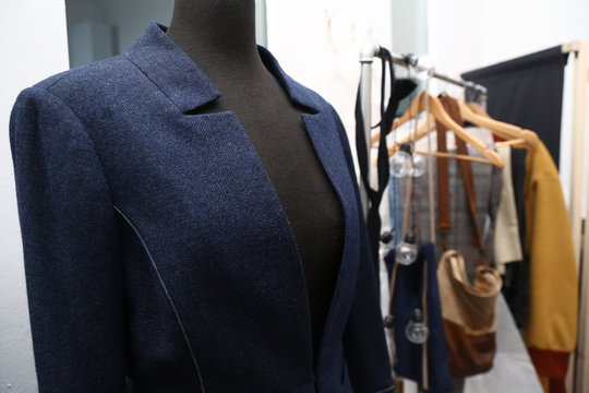 Tailor´s dummy with a blue jacket and a clothes rack in a tailor´s studio