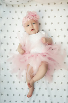 Little smiling baby girl sweet ballerina with fluffy pink skirt and flower in the cradle. Happy childhood. top view