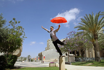 Young man balancing with a red umbrella