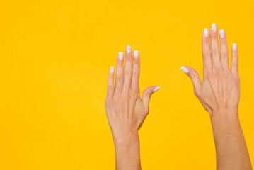 Woman hands over yellow background with copyspace