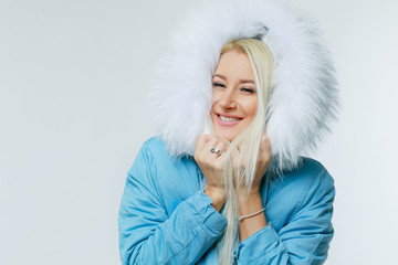 Fashion portrait of young beautiful blond woman with fur. white fur hood. winter style. Copy space for text on left side