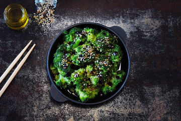 Broccoli baked in a cast iron skillet. Healthy Chinese style food. Vegan snack. Food sticks. Serve baked broccoli with sauces and sesame seeds.