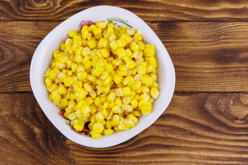 Canned sweet corn in a bowl on wooden table