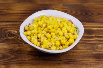 Canned sweet corn in a bowl on wooden table