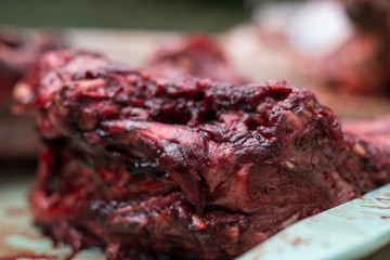 Closeup of bloody raw meat on a tray, background out of focus
