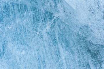 Close-up wall of a centuries-old glacier with a structure of stripes and bubbles. Ice blue light texture