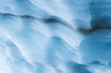 Obraz premium Close-up blurred wall of a centuries-old glacier with a structure of stripes and bubbles. Ice blue light texture