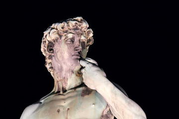 Closeup of the bronze copy of the David of Michelangelo at night with black background, Florence Italy