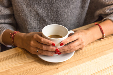 White cup of coffee in female hands. Warm your hands with a cup of hot drink. Meeting in a cafe....