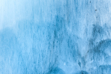 Close-up wall of a centuries-old glacier with a structure of stripes and bubbles. Ice blue light texture