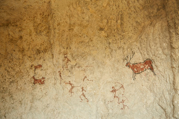 Rock paintings of hunters and wild animals in a cave