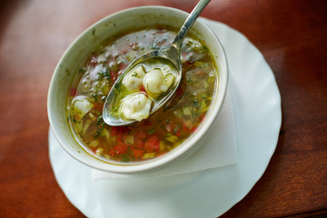 Soup with dumplings in a small deep white plate