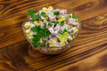 Obraz na płótnie Canvas Tasty salad with sausage, green pea, canned corn, bell pepper, cucumber and mayonnaise on wooden table