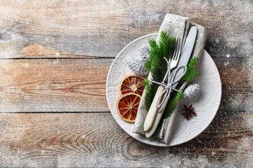 Christmas table setting with christmas decorations. White plate, Cutlery, fir cones and towel with...