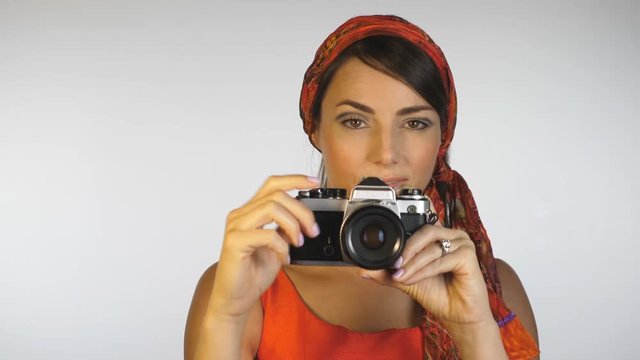 1960s 1970s style. Attractive woman in orange shoots w 35mm film camera.