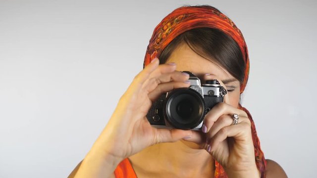 1960s 1970s style. Attractive woman in orange shoots w 35mm film camera.