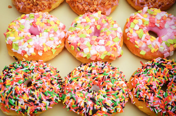 donuts background / set of various colorful donuts top view on tray - delicious sweet donut with sprinkles sugar 