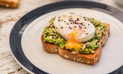 Close up food photography of an avocado toast with poached egg and sesame seeds. Breakfast, lunch,...