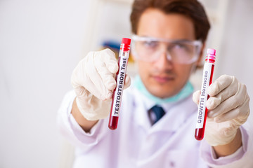 Young handsome lab assistant testing blood samples in hospital 