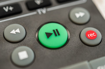 Close up macro photography of a smart tv television remote control with play button. Concept of entertainment, fun, and news