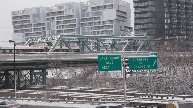 Queen Street Viaduct crossing the Don River and DVP in Toronto. Streetcar passing with snow falling. Winter. Handheld shot with stabilized camera. 
