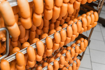 Smoked sausages hanging on a metal frame in the smokehouse.