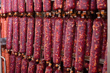 Dried sausage hanging on a rope on a metal frame in the smoke house. Moscow sausage. Braungschwei sausage. Kurkhan.