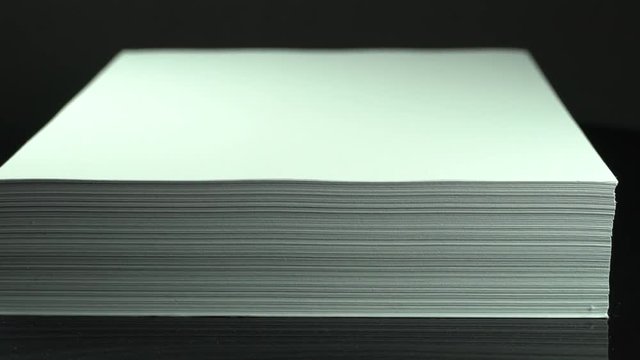 a ream of blank a4 paper turning around on black background