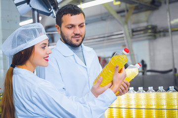 A man and a woman in white overalls against the background of a line for the production of...