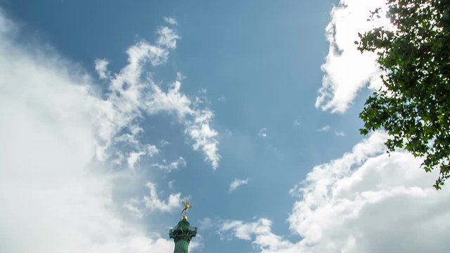 Establishing shot of place Bastille with traffic on a sunny day, tilting downwards.